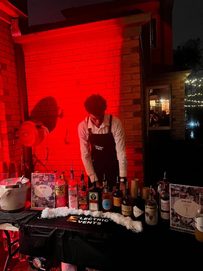 Electric Events outdoor bar setup with spirits and drinks menus at night