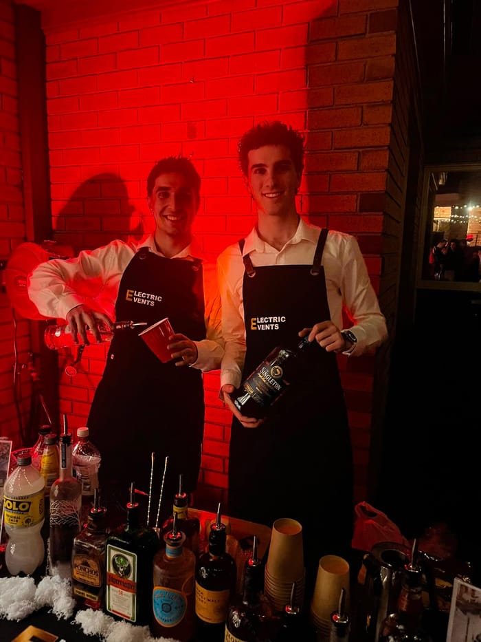 Two Electric Events bartenders pouring drinks under red lighting